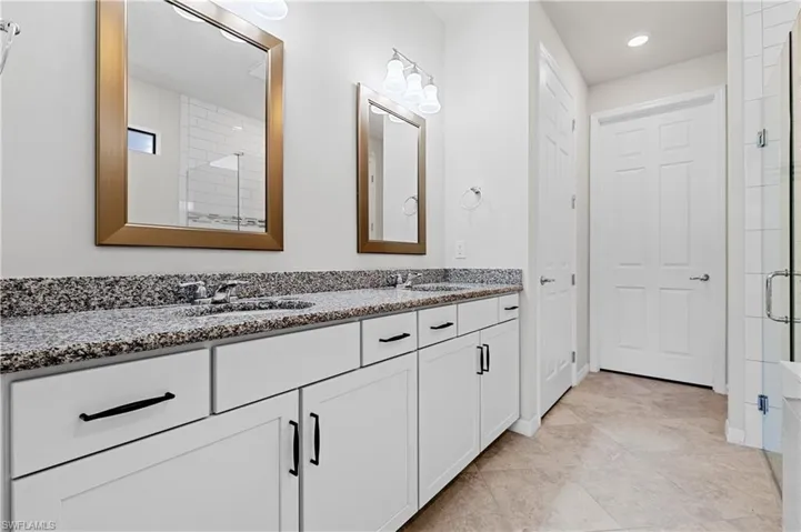 Bathroom featuring double vanity, a stall shower, and light tile patterned floors