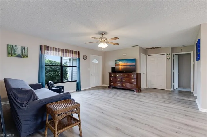 Living room featuring light wood-style flooring, a textured ceiling, and a ceiling fan