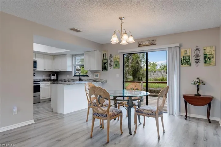 Dining room with healthy amount of natural light, a textured ceiling, light wood-style flooring, and a chandelier