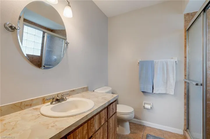 Full bath featuring light tile patterned flooring, vanity, and a stall shower