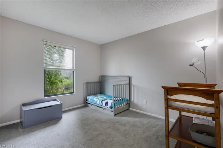 Bedroom featuring a crib, carpet flooring, and a textured ceiling