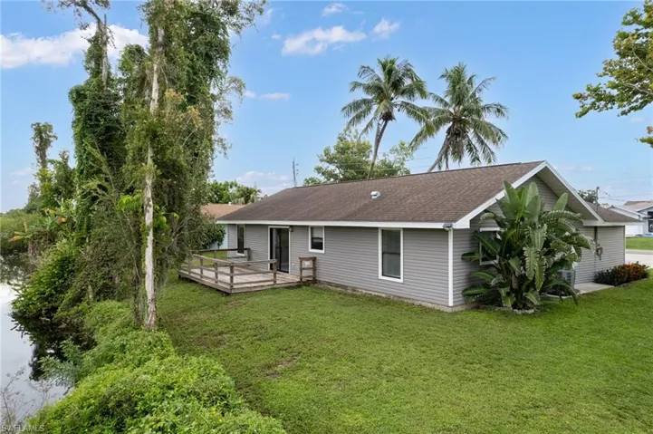 Back of property with a deck, a yard, and a shingled roof