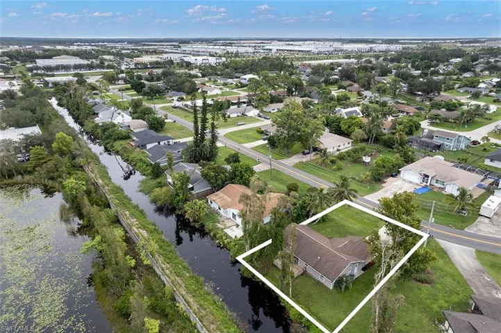 Aerial perspective of suburban area with property parcel outlined and a nearby body of water
