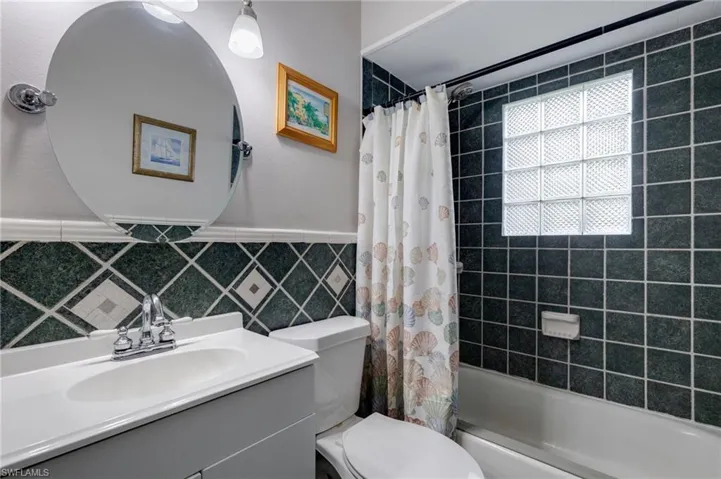Full bath with vanity, shower / tub combo, and tile walls