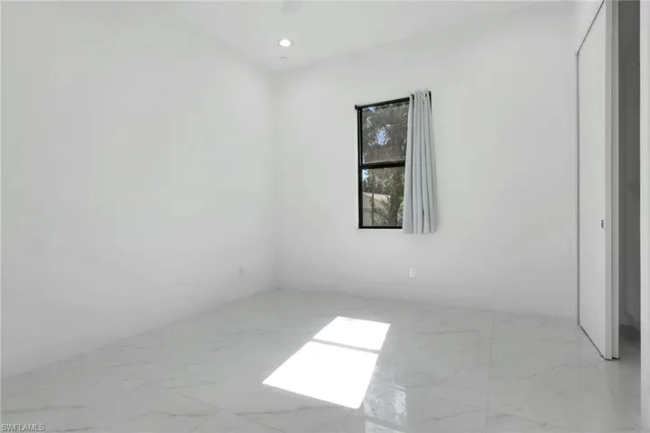Empty room featuring light marble finish flooring and recessed lighting