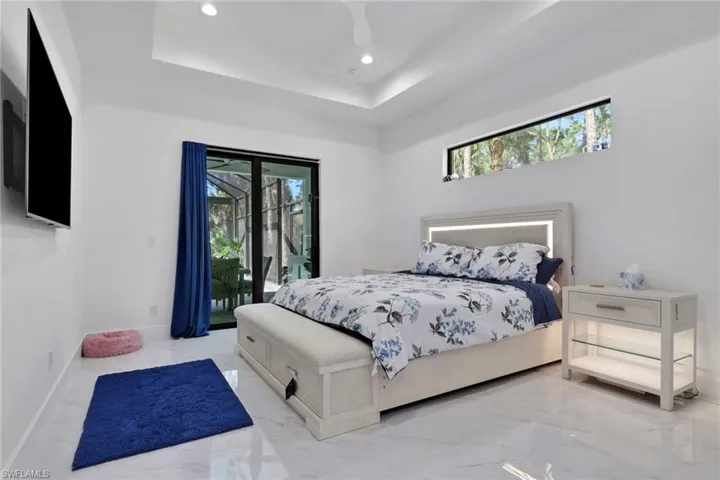 Bedroom featuring multiple windows, recessed lighting, access to outside, a raised ceiling, and marble tiled flooring