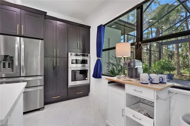 Kitchen featuring appliances with stainless steel finishes, light marble finish flooring, wood counters, and white cabinets