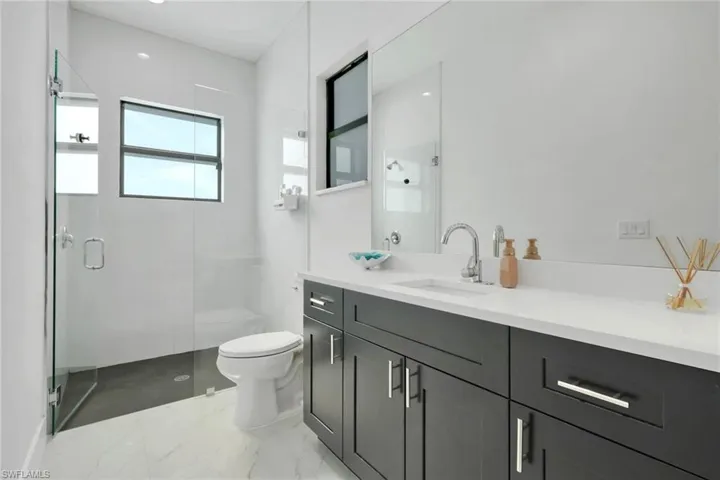 Bathroom featuring vanity, a shower stall, light marble finish floors, and recessed lighting