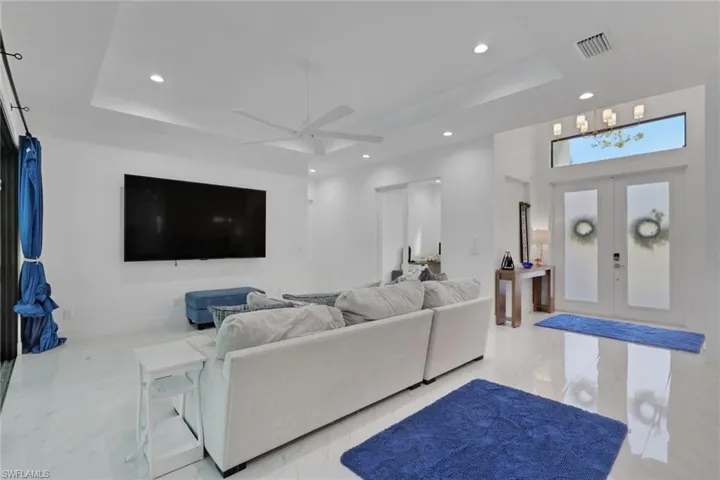 Living area featuring a raised ceiling, french doors, recessed lighting, and ceiling fan