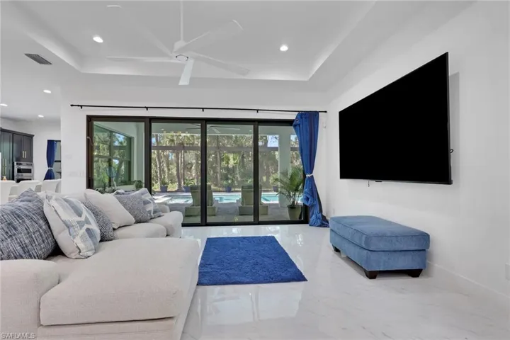 Living room with a ceiling fan, marble tiled flooring, a tray ceiling, and recessed lighting
