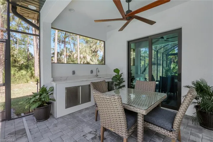 Sunroom / solarium featuring an outdoor kitchen, ceiling fan, outdoor dining space, and a patio area