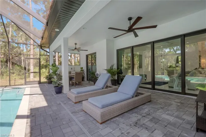 View of patio / terrace with an outdoor pool, a sunroom, glass enclosure, outdoor dining space, and a ceiling fan