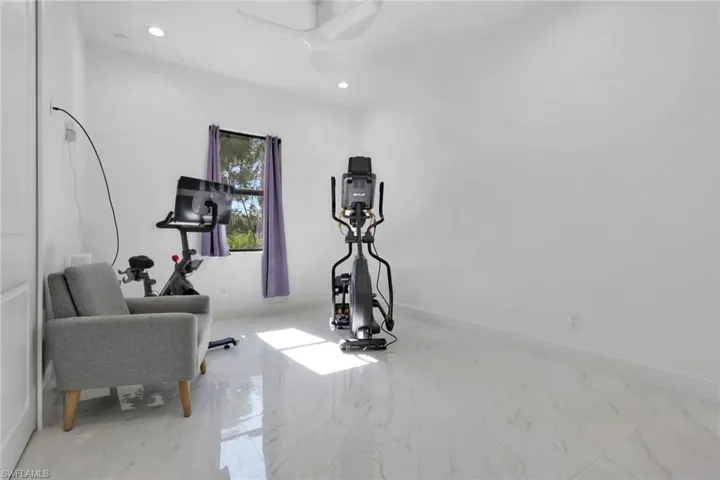 Workout area with light marble finish floors and recessed lighting