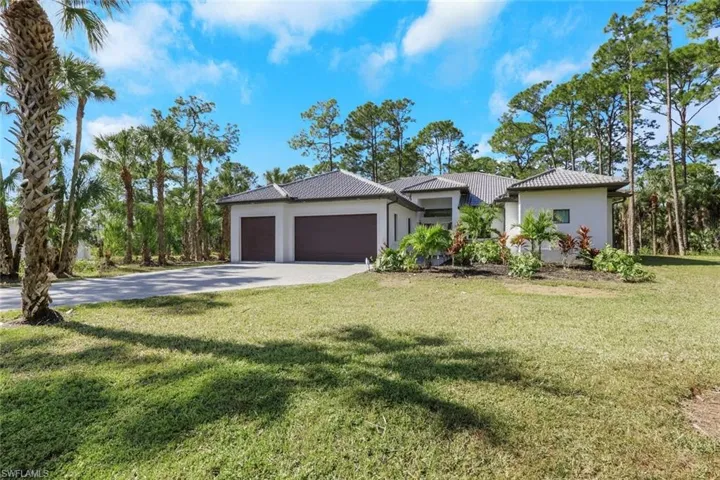 View of front of house featuring a front lawn, stucco siding, an attached garage, and driveway