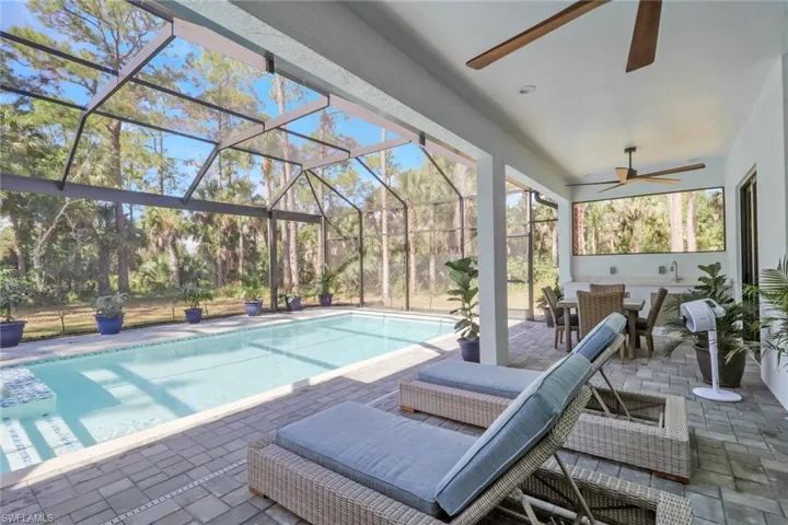 Swimming pool featuring a patio, glass enclosure, a sunroom, outdoor dining area, and ceiling fan