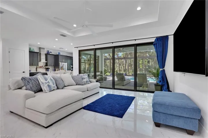 Living area featuring a ceiling fan, recessed lighting, marble tiled floors, and a tray ceiling