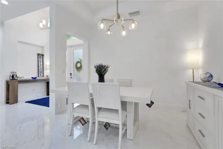 Dining room featuring light marble finish floors and a chandelier