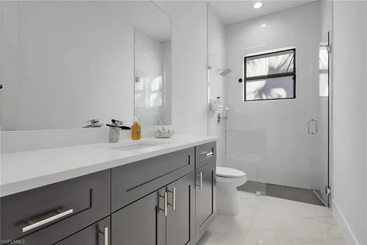 Full bath with vanity, a stall shower, light marble finish flooring, and recessed lighting