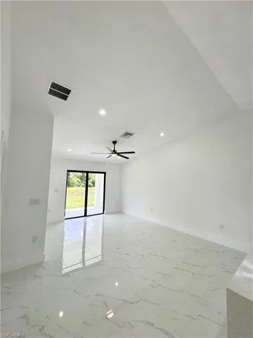 Empty room featuring light marble finish floors and a ceiling fan