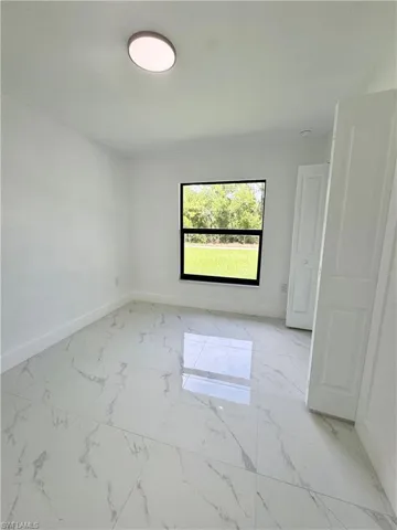 Unfurnished bedroom featuring light marble finish floors and a closet