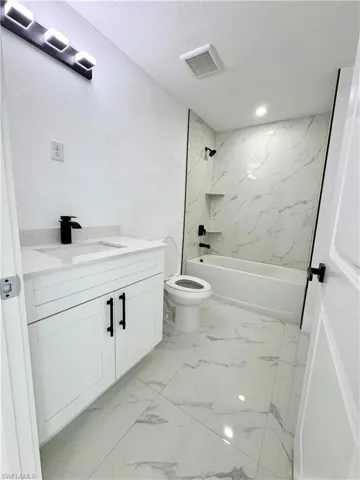 Bathroom with vanity, shower / bath combination, and a textured ceiling