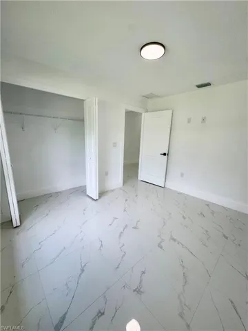 Bathroom featuring a marble finish shower, vanity, light marble finish floors, and recessed lighting