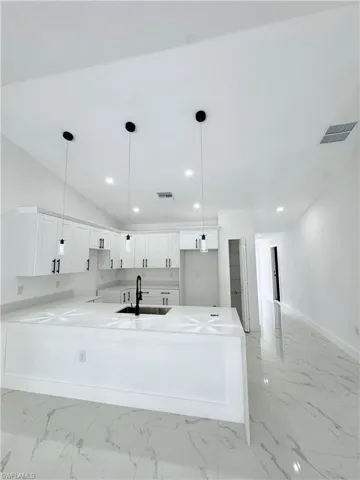 Kitchen with white cabinets, light stone counters, a peninsula, hanging light fixtures, and recessed lighting