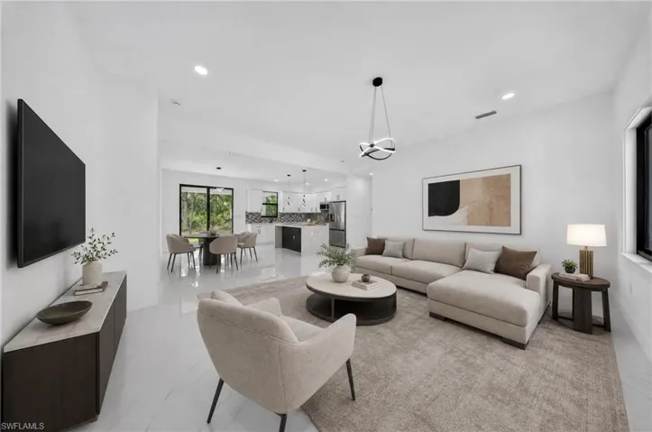 Open-concept living space featuring high ceilings, recessed lighting, and large format tile flooring