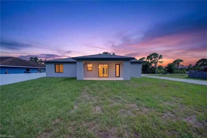 Rear exterior featuring a covered patio, multiple windows, and a spacious grassy yard