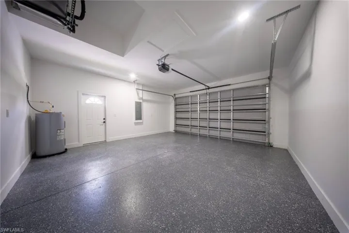 Spacious garage featuring a durable speckled epoxy floor, white interior walls, and an automatic garage door opener