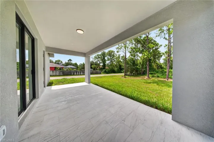 Covered outdoor patio featuring light-toned large format tile flooring, recessed ceiling lighting, and a stucco finish