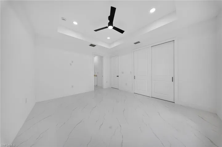 Spacious room featuring white walls and large format tile flooring