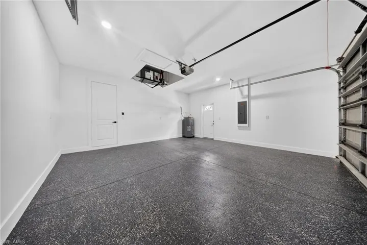 Spacious garage featuring a durable epoxy floor, white walls, and bright overhead lighting