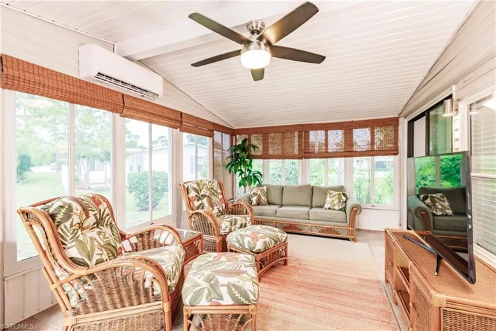 Sunroom featuring vaulted ceiling with beams, ceiling fan, and a wall mounted air conditioner