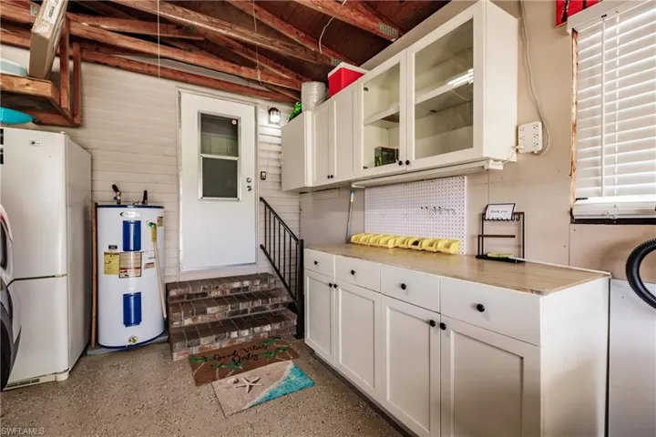 Kitchen featuring electric water heater, white cabinets, and white fridge