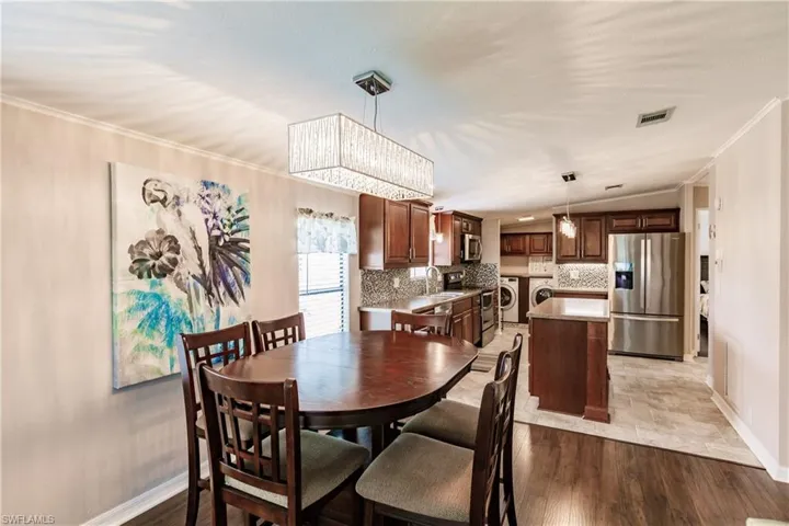 Dining area featuring lofted ceiling, independent washer and dryer, light hardwood / wood-style floors, sink, and ornamental molding