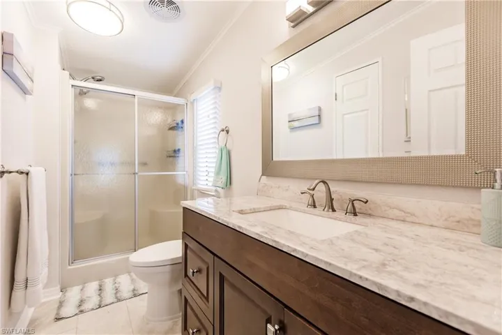 Bathroom with vanity, ornamental molding, tile patterned flooring, and toilet