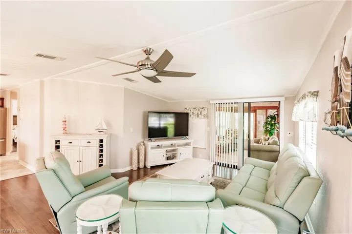Living room featuring hardwood / wood-style flooring, ornamental molding, and ceiling fan
