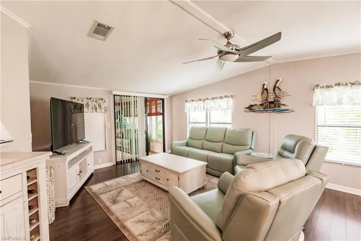 Living room with vaulted ceiling, a wealth of natural light, ceiling fan, and dark hardwood / wood-style floors
