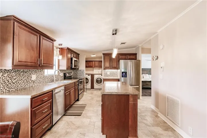 Kitchen with washing machine and dryer, pendant lighting, sink, appliances with stainless steel finishes, and light tile patterned floors