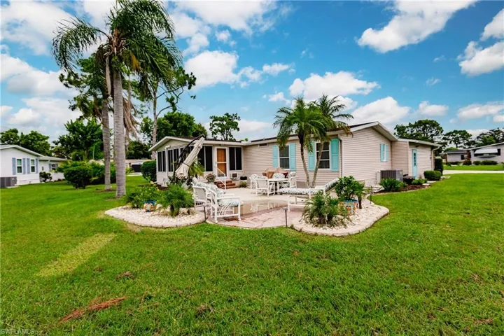 Back of property with central air condition unit, a patio area, a sunroom, and a yard