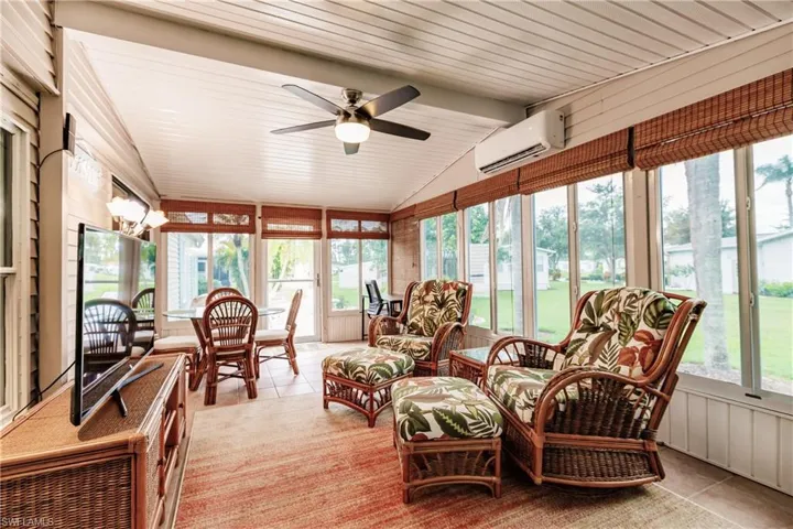 Sunroom featuring a wall mounted AC, lofted ceiling, and ceiling fan