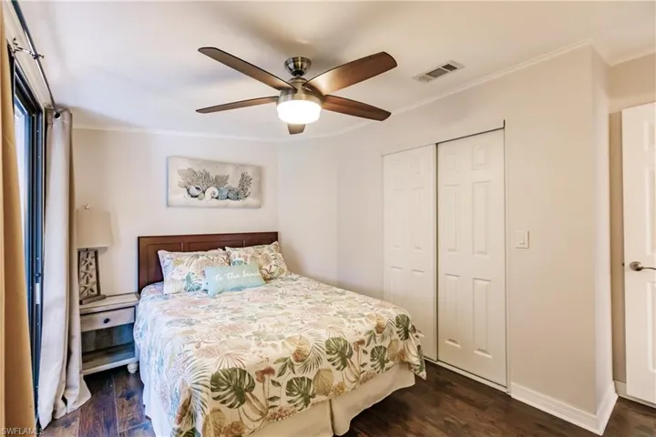 Bedroom featuring ceiling fan, dark wood-type flooring, a closet, and crown molding