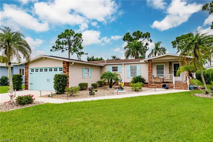 Single story home featuring covered porch, a garage, and a front lawn