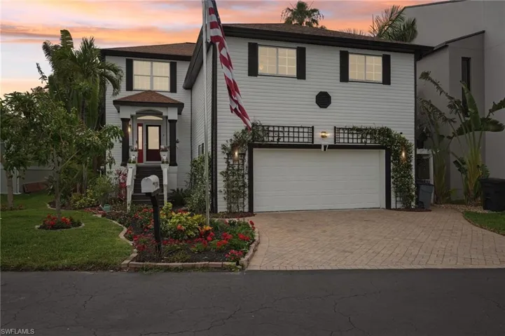 View of front facade with a yard, a garage, and decorative driveway