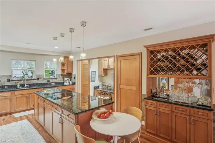 Kitchen featuring black electric stovetop, light wood-style flooring, open shelves, a kitchen island, and a sink