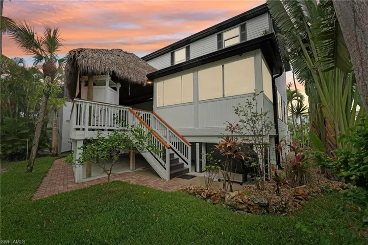 Back of house at dusk with a yard and stairs