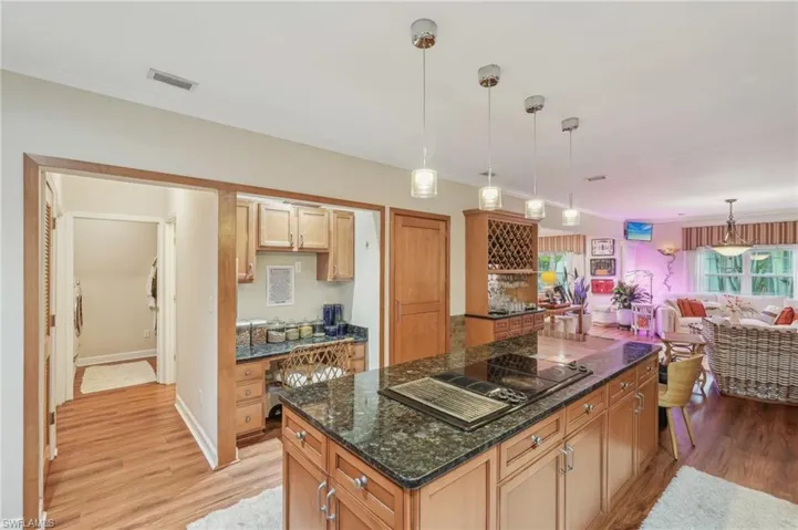Kitchen with light wood-style flooring, visible vents, a kitchen island, decorative light fixtures, and black electric stovetop