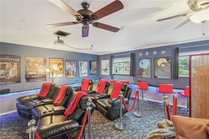 Cinema featuring ornamental molding, visible vents, a ceiling fan, and carpet