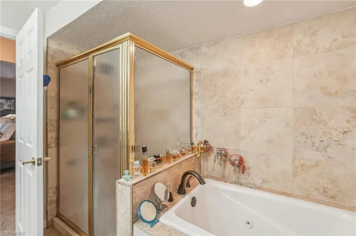 Bathroom featuring a stall shower, a jetted tub, and connected bathroom